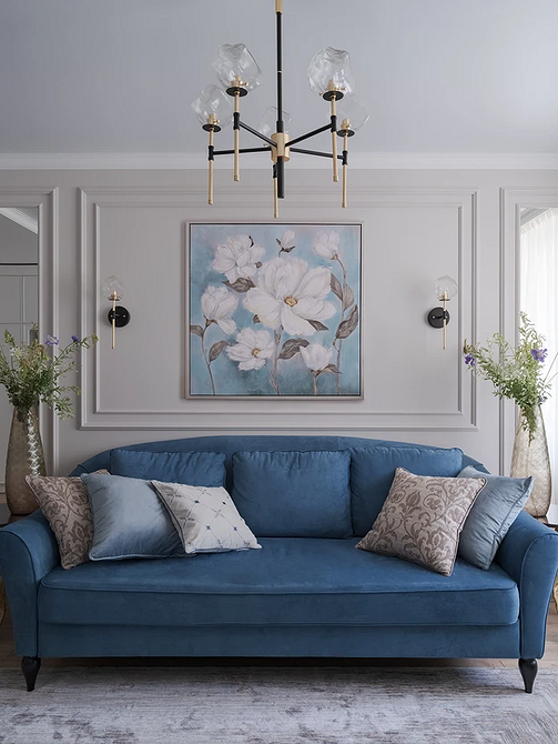 Інтер'єр кімнати з синім диваном, картинами на стінах і м'яким освітленням, дизайн меблів.