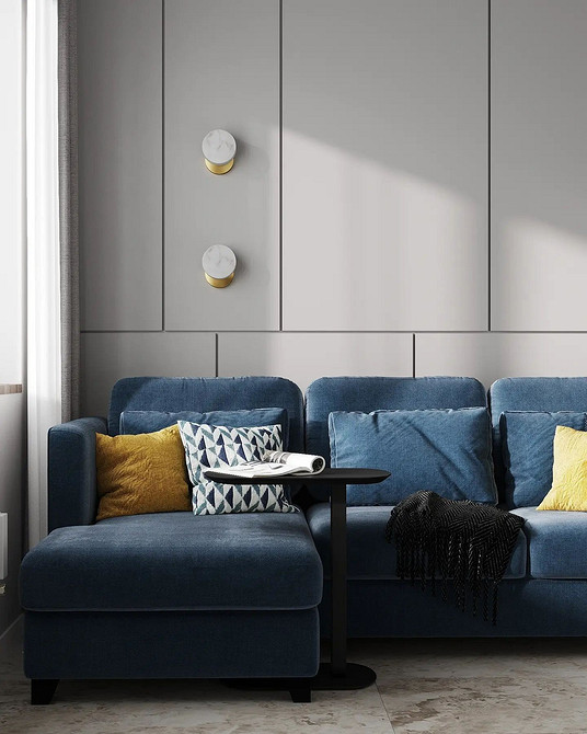 Вітальня з великим синім диваном, полицями з книгами та зеленими рослинами