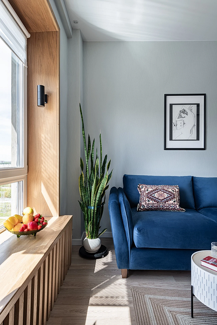 Затишна вітальня з синім диваном, подушками та пледом, скандинавський стиль.