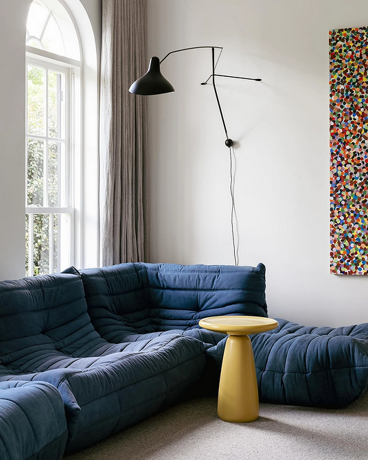 Елегантний кутовий диван сірого кольору в мінімалістичному інтер'єрі, стильний акцент кімнати.