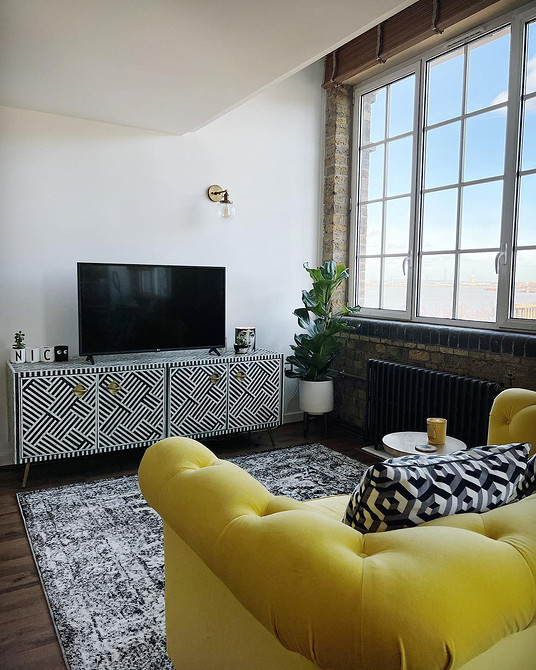 Інтер'єр вітальні з жовтим диваном, журнальним столиком та декоративним освітленням.