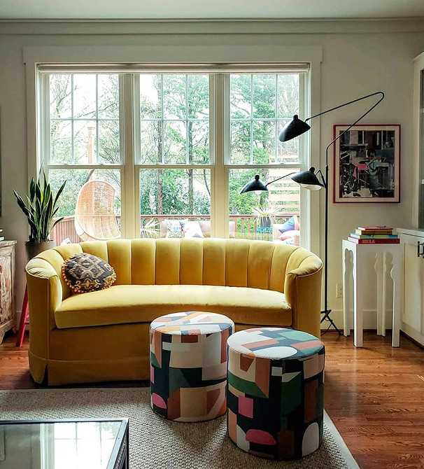 Невеликий жовтий диванчик в маленькій квартирі-студії з білими меблями
