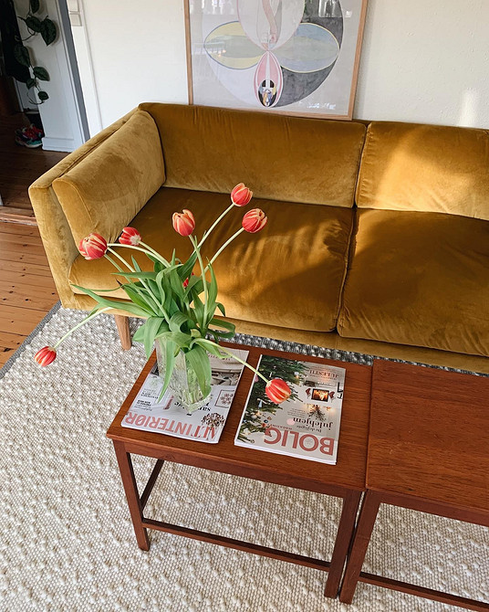 Жовтий диван з оббивкою з велюру в інтер'єрі з акцентною стіною та освітленням