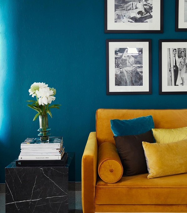 Жовтий диван у вітальні з сірими стінами та декоративними подушками створює затишок.