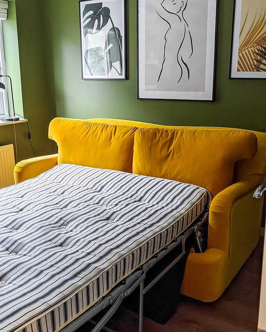 Жовтий диван у скандинавському інтер'єрі з рослинами та дерев'яними елементами виглядає гармонійно.