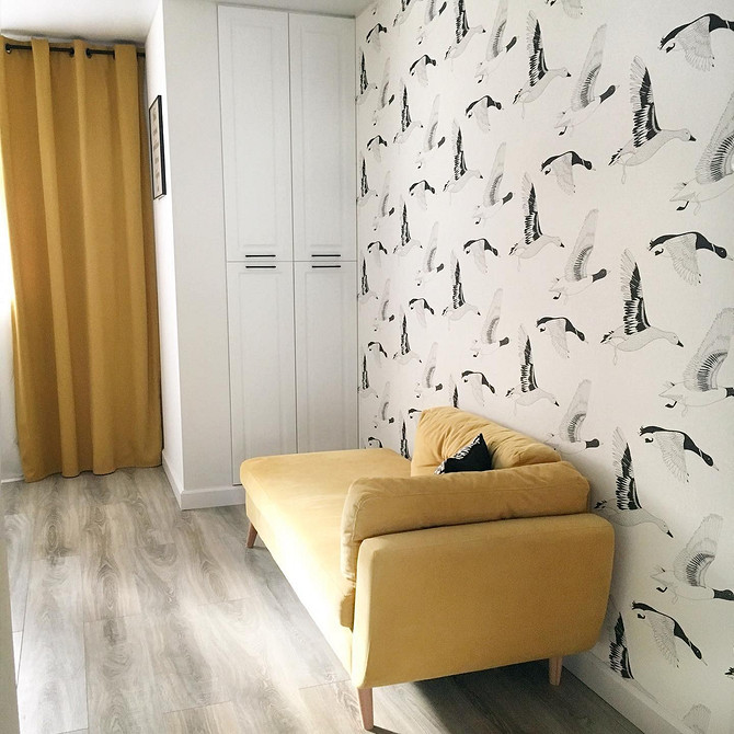 Мінімалістичний інтер'єр з жовтим диваном, білими стінами та яскравими елементами декору.