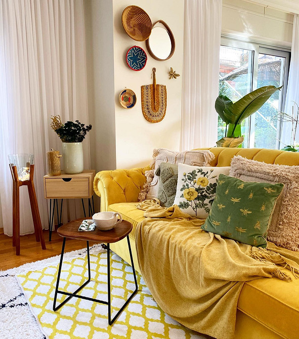 Жовтий диван у вітальні з сірими стінами та декоративними подушками створює затишок