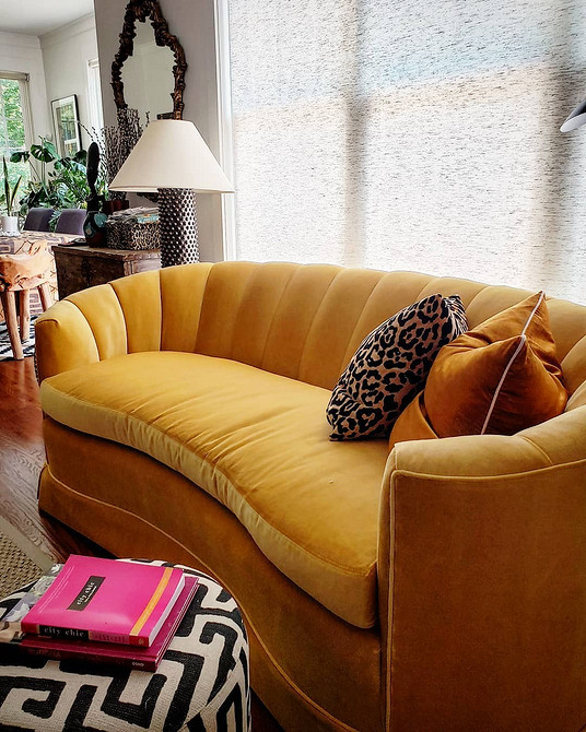 Сучасний інтер'єр з жовтим диваном, різнокольоровими подушками та дерев'яною підлогою у вітальні.