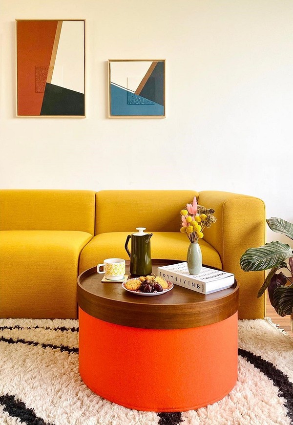 Жовтий кутовий диван у світлій вітальні з дерев'яними елементами в скандинавському стилі.