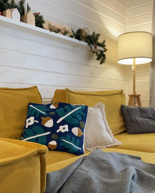 Інтер'єр вітальні з жовтим диваном, каміном та декоративними подушками.