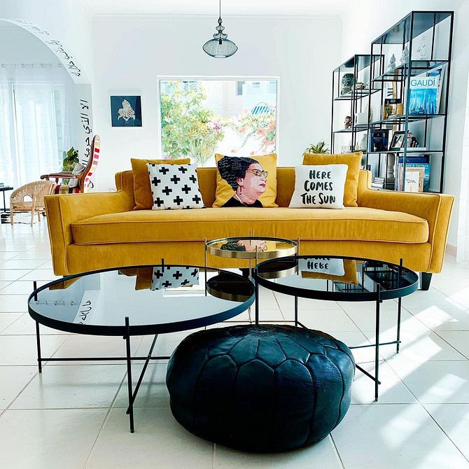 Дизайн інтер'єру з жовтим диваном, книжковою шафою та зеленими рослинами у горщиках.