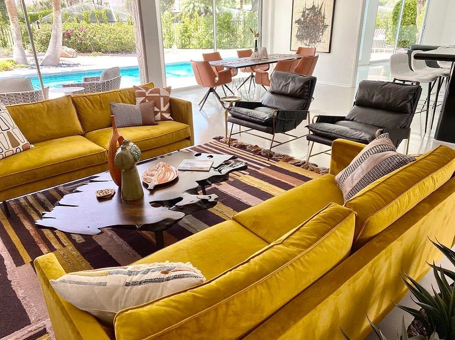 Жовтий кутовий диван у просторій вітальні з великими вікнами та чудовим освітленням