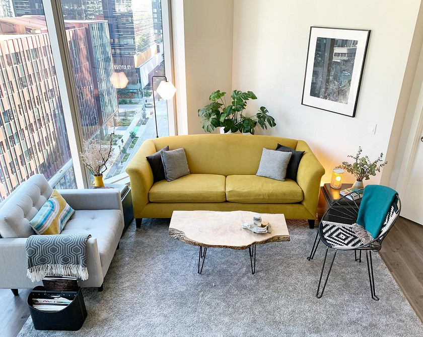Стильний жовтий диван в інтер'єрі з використанням сірих та білих кольорів у вітальні.