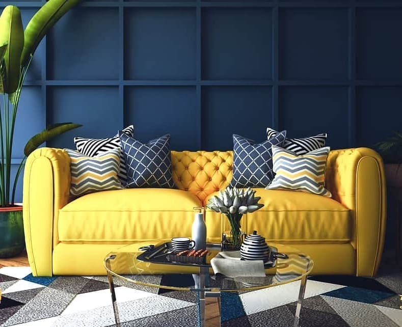 Жовтий диван з подушками різних кольорів на фоні білих стін.