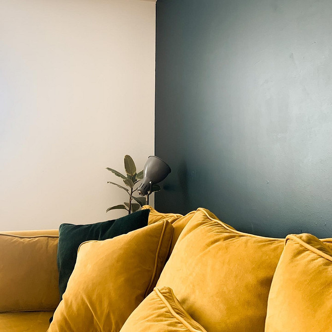 Жовтий кутовий диван у вітальні з великим вікном та панорамним видом на місто