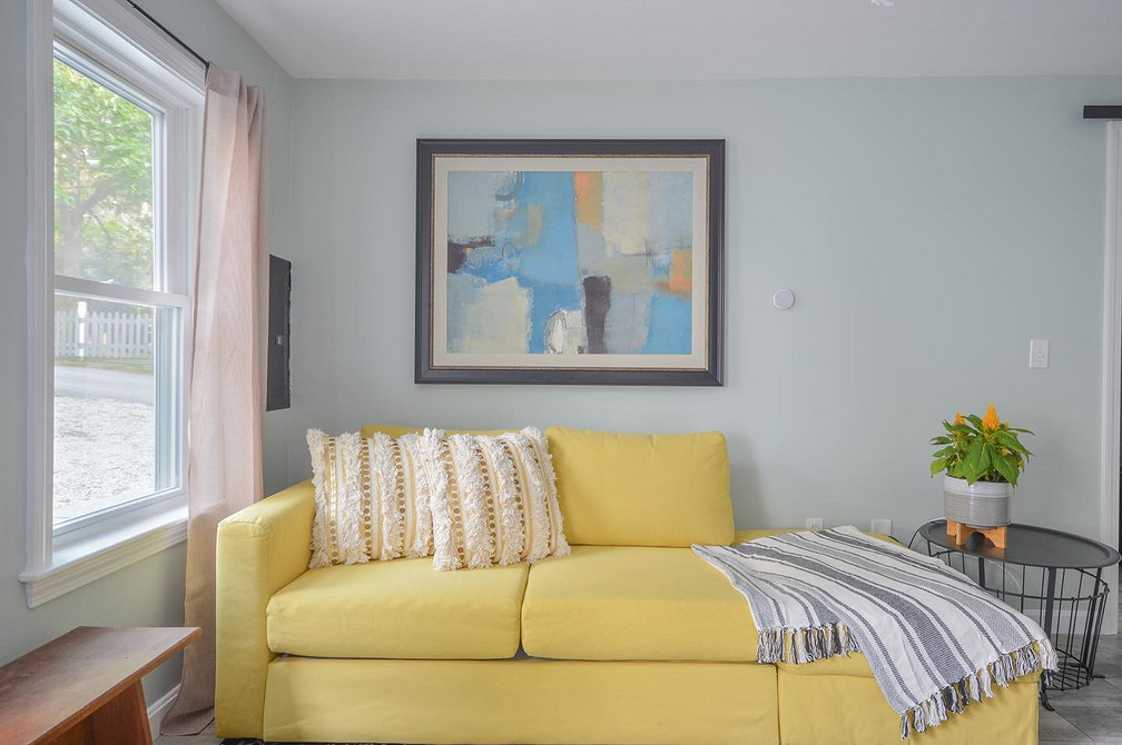 Жовтий велюровий диван в інтер'єрі з акцентною стіною та сучасним освітленням.