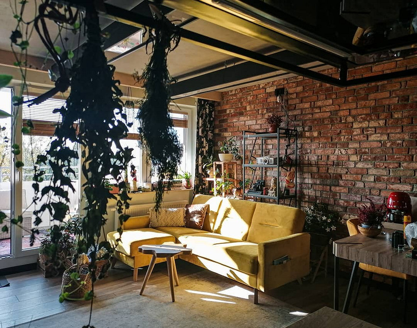 Жовтий диван з текстильною оббивкою в інтер'єрі з рослинами та світлом